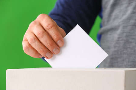 Voting man near ballot box on color backgroundの写真素材