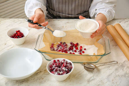 Woman preparing tasty sugared cranberry in kitchenの写真素材
