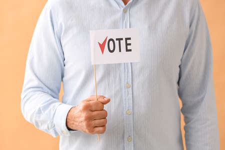 Man holding flag with text VOTE on color backgroundの写真素材