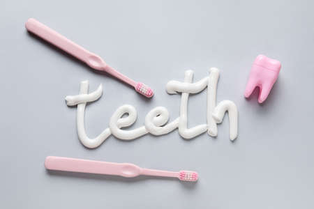 Toothbrushes, dental floss and word TEETH written with toothpaste on gray backgroundの写真素材