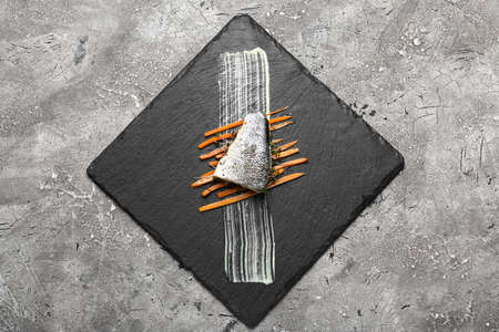 Board of tasty sea bass fish on grunge background