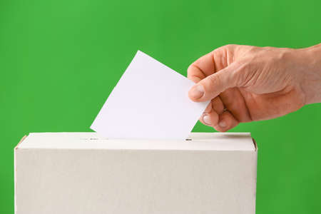 Voting man near ballot box on color background