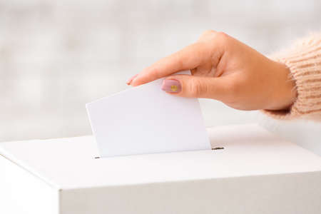 Voting woman near ballot box on light background, closeup