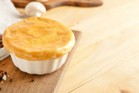 Board with tasty vegetable pot pie on wooden background