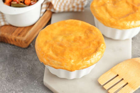 Board with tasty vegetable pot pies on grunge background