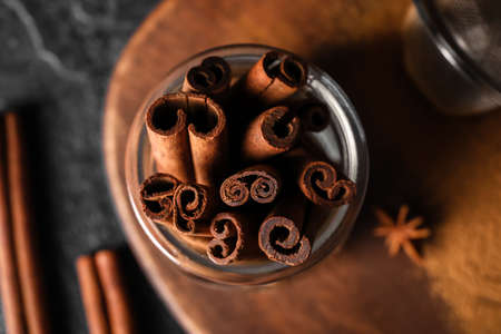 Jar of natural cinnamon sticks on black background, closeup
