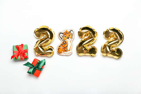 Balloons in shape of figure 2022, tiger cookie and gift boxes on white background