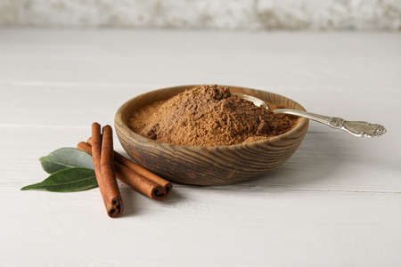 Bowl with cinnamon powder and sticks on white wooden backgroundの写真素材