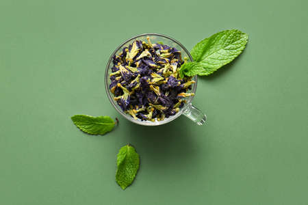 Glass cup of dried butterfly pea flower tea on color backgroundの写真素材