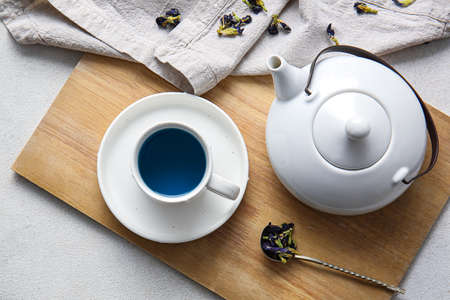 Teapot and cup of organic blue tea on light backgroundの写真素材