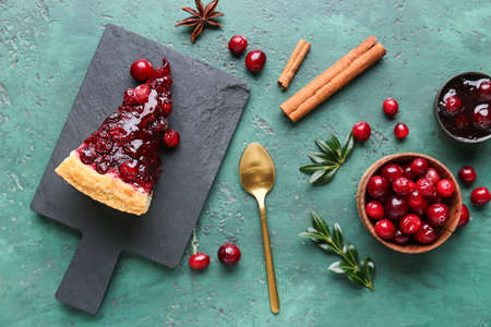 Board with piece of tasty lingonberry pie, jam and spices on color backgroundの写真素材
