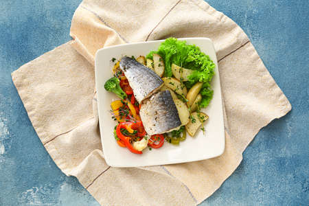 Plate of tasty sea bass fish with vegetables on blue backgroundの写真素材