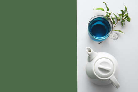 Teapot and glass cup of organic blue tea on color backgroundの写真素材