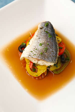 Plate of tasty sea bass fish with vegetables on table