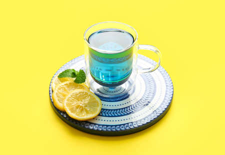 Glass cup of organic blue tea and lemon on yellow backgroundの写真素材
