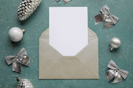 Envelope with blank card and silver Christmas decor on grunge background