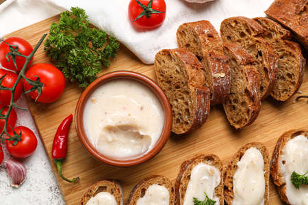 Bowl of lard spread, vegetables and bread on light background
