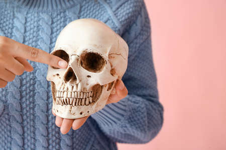 Young woman with human skull on color background, closeupの写真素材