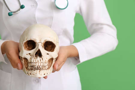Female doctor with human skull on color background, closeupの写真素材