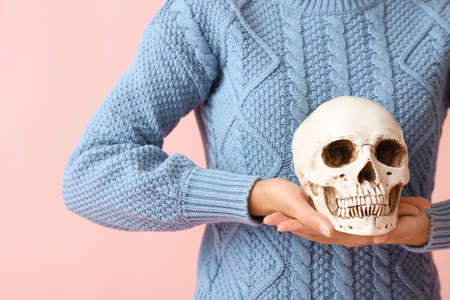 Young woman with human skull on color background, closeupの写真素材