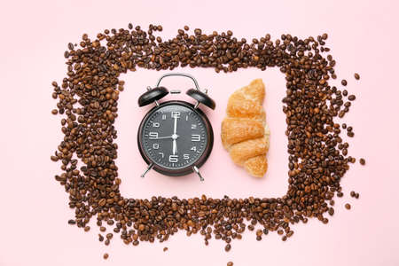 Composition with coffee beans, croissant and alarm clock on pink backgroundの写真素材