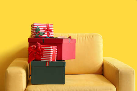 Different gift boxes on armchair near color wall