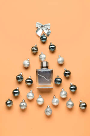 Christmas tree made of perfume bottle and balls on color background