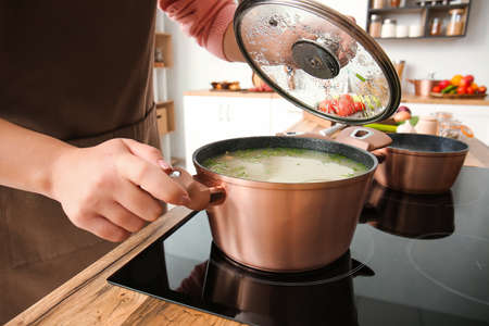 Housewife cooking tasty soup in pot at home, closeupの写真素材