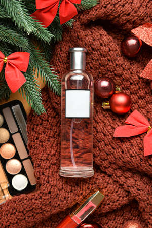 Bottle of perfume and Christmas decorations on sweater, closeup