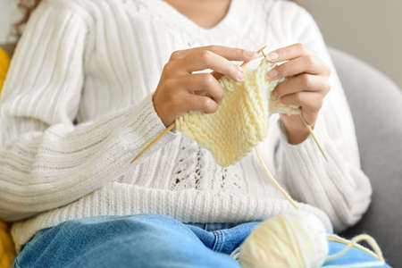 Young African-American woman knitting at home, closeup