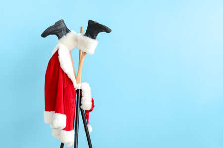 Hanger with Santa Claus costume and boots on color backgroundの写真素材