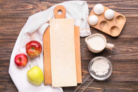 Fresh dough and ingredients for apple strudel on wooden background