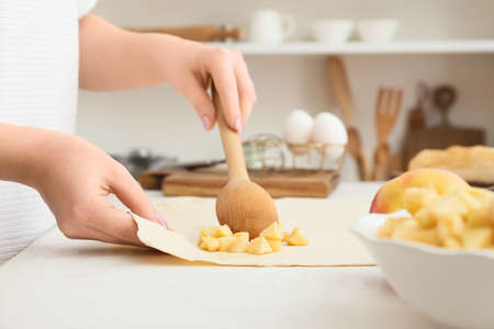 Woman preparing apple strudel at table in kitchen