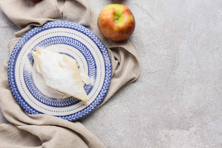 Plate with piece of tasty apple strudel on light background