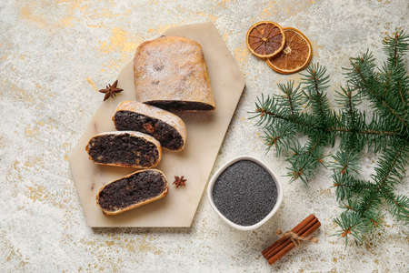 Board with cut poppy seed strudel on light backgroundの写真素材