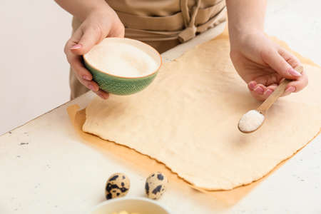 Woman preparing apple strudel at table in kitchen