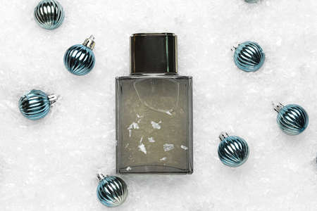 Bottle of perfume and Christmas balls on snow backgroundの写真素材