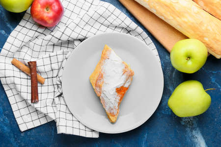 Plate with pieces of tasty apple strudel and fresh fruits on blue backgroundの写真素材