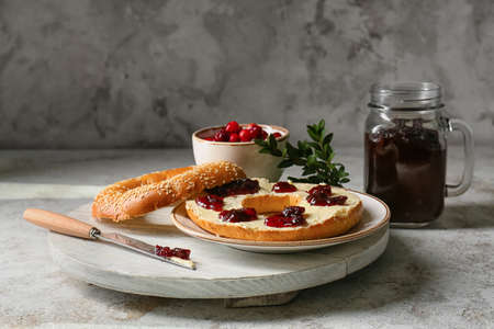 Bagel with tasty lingonberry jam on grunge background