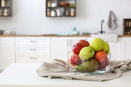 Bowl with fruits and napkin on table in light kitchenの写真素材