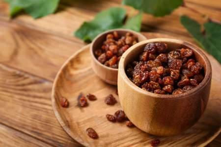 Bowls with tasty raisins on wooden background, closeupの写真素材