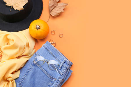 Trendy female accessories, pumpkin and dry leaves on color backgroundの写真素材