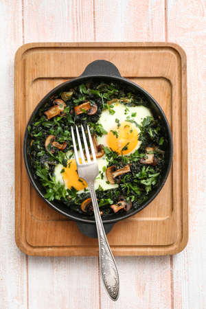 Frying pan with tasty Shakshouka on white wooden background