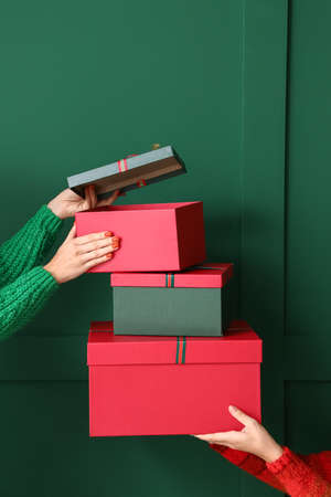 Women with Christmas gift boxes near green wall