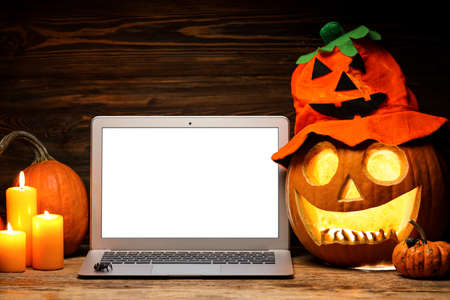 Carved pumpkin for Halloween and laptop on dark backgroundの写真素材