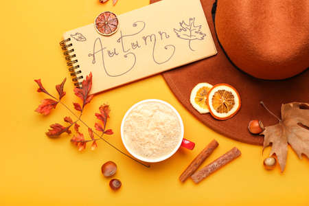 Composition with cup of coffee and text AUTUMN on color background