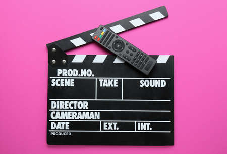 Modern TV remote control and clapperboard on pink backgroundの写真素材