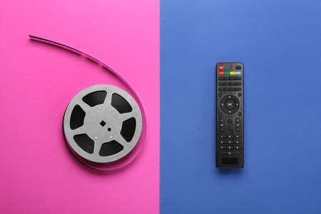 Modern TV remote control and film reel on color backgroundの写真素材