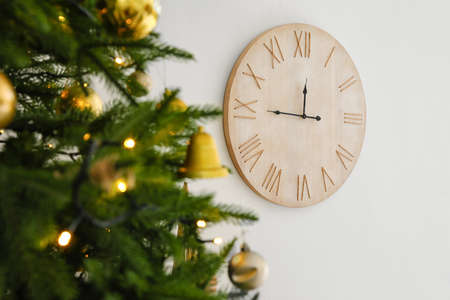 Christmas tree and big wooden clock on light wall