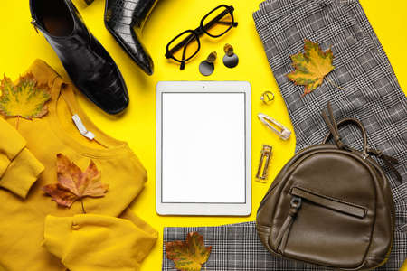 Stylish female accessories, clothes, tablet computer and dry leaves on color background. black friday saleの写真素材